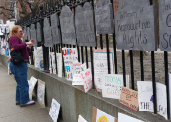 AME5885. BOSTON (ESTADOS UNIDOS), 05/04/2025.- Una mujer observa algunos carteles durante una protesta denominada 'Hands Off' este sábado, en Boston (Estados Unidos). Miles de personas participaron este sábado en protestas convocadas en un millar de ciudades y municipios de Estados Unidos, como Washington y Nueva York, en contra de los recortes y otras políticas del presidente, Donald Trump, a quien acusan de autoritario. EFE/ Iñaki Estívaliz