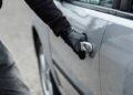 Close up on car thief hand pulling the handle of a car. Car thief, car theft concept
