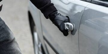 Close up on car thief hand pulling the handle of a car. Car thief, car theft concept