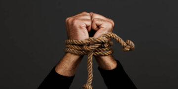 Hands  tied with rope, on dark background