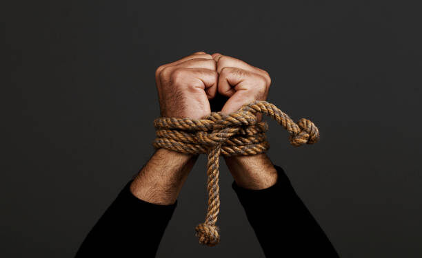 Hands  tied with rope, on dark background