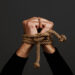 Hands  tied with rope, on dark background
