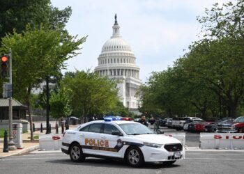 A US Capitol police officer stands by his car outside the Russell Senate Office Building in Washington, DC, on August 2, 2023, after unconfirmed eports of an active shooter in the building near the US Capitol. (Photo by SAUL LOEB / AFP)