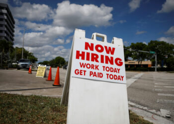 A "Now Hiring" sign advertising jobs at a hand car wash is seen along a street, as the spread of the coronavirus disease (COVID-19) continues, in Miami, Florida, U.S. May 8, 2020. REUTERS/Marco Bello