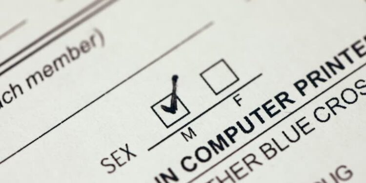 Person checking the male gender box on a document form with black pen