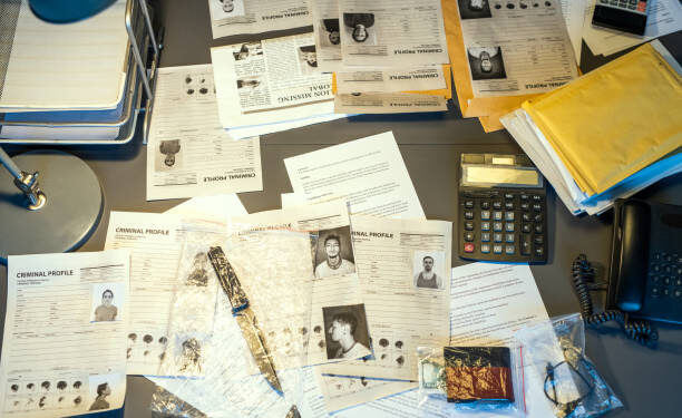 Part of workplace of contemporary fbi agent with criminal profiles, calculators, telephone, packets with clues and other stuff