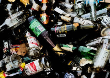 Sittingbourne, United Kingdom – November 16, 2021: A close-up top view of a pile of discarded alcoholic glass drink bottles