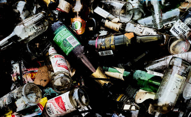 Sittingbourne, United Kingdom – November 16, 2021: A close-up top view of a pile of discarded alcoholic glass drink bottles