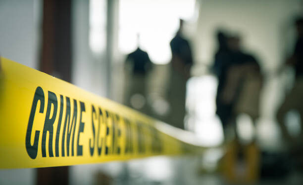 crime scene tape with blurred forensic law enforcement background in cinematic tone and copy space