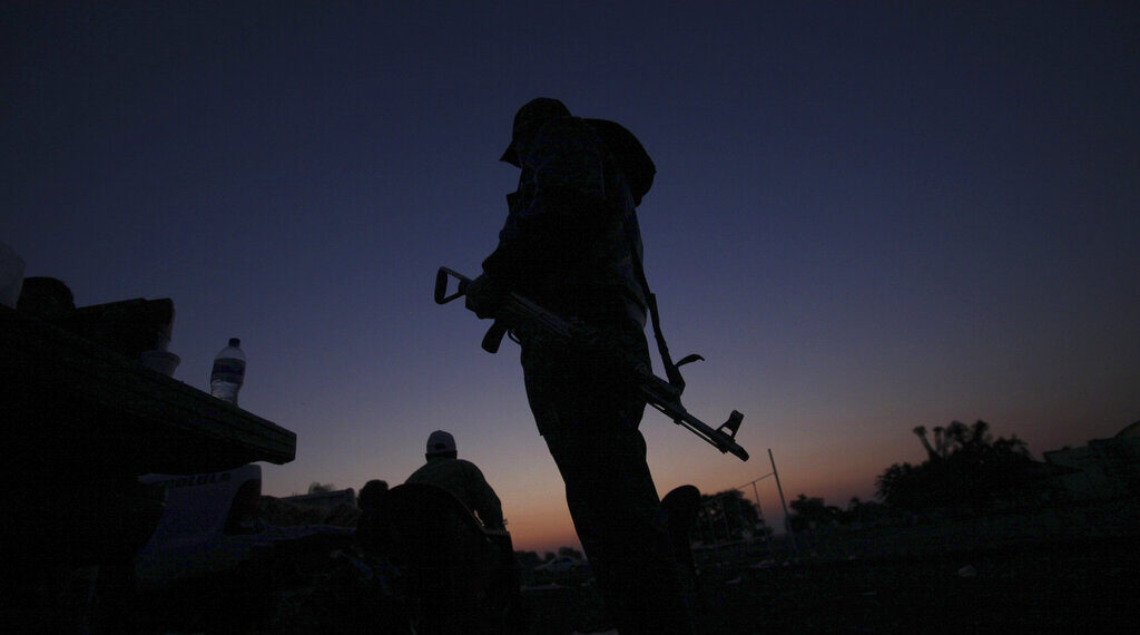 FILE - In this Feb. 9, 2014, file photo, an armed man from a self-defense group stands with his weapon at the entrance of Apatzingan in Michoacan state, Mexico. Prosecutors in western Mexico announced this Wednesday April 16, 2014 that they arrested the mayor of Apatzingan that once served as a stronghold of the Knights Templar drug cartel on charges that he helped the gang extort money from city council members. (AP Photo/Marco Ugarte, File)