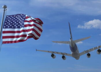 Commercial airplane landing behind waving flag