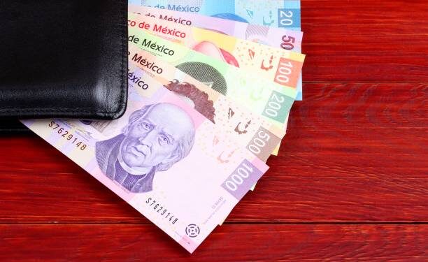 Mexican Pesos in the black wallet on a wooden background