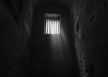 A small window in the dark room, with light coming from outside, black and white photography.