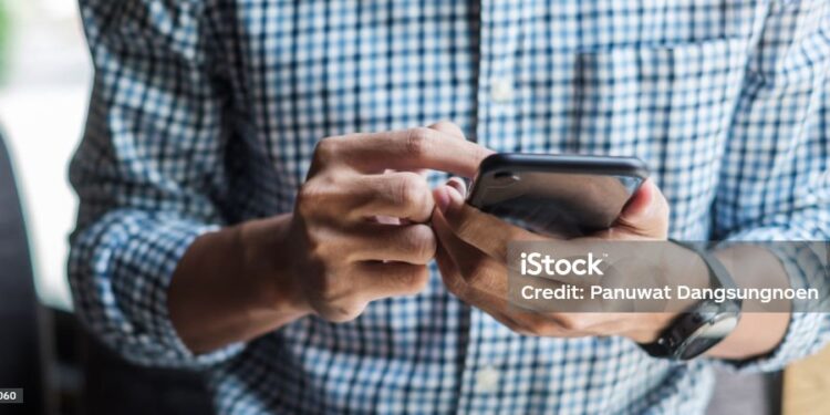 Young casual Businessman holding and using smartphone for sms messages, hipster man typing touchscreen cell phone in the cafe. business, lifestyle, technology and Social media network concept