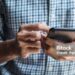 Young casual Businessman holding and using smartphone for sms messages, hipster man typing touchscreen cell phone in the cafe. business, lifestyle, technology and Social media network concept
