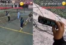 Mujer sostiene un teléfono hacia la cancha mientras revisa chats durante un partido