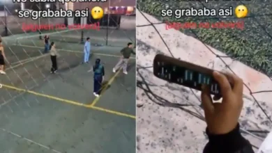 Mujer sostiene un teléfono hacia la cancha mientras revisa chats durante un partido