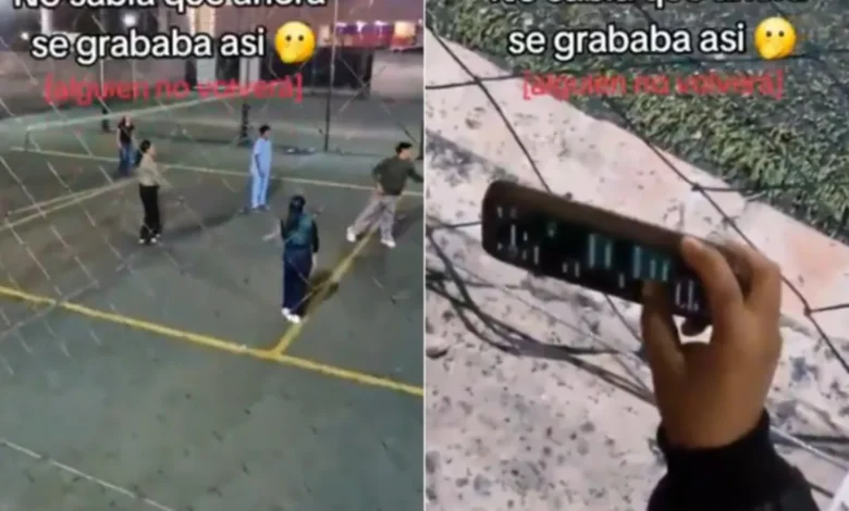 Mujer sostiene un teléfono hacia la cancha mientras revisa chats durante un partido