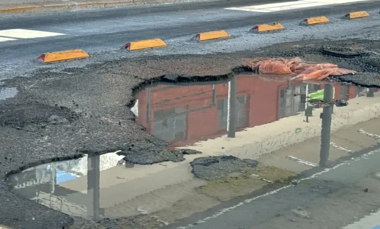 Agua acumulada por una fuga oculta baches en la calle Manuel Bernal de Ciudad Juárez